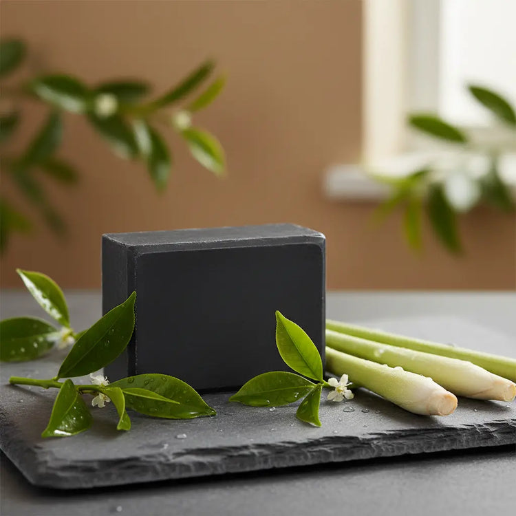 Black Flag Ballast Cut soap bar on slate with fresh lemongrass stalks and tea tree leaves.