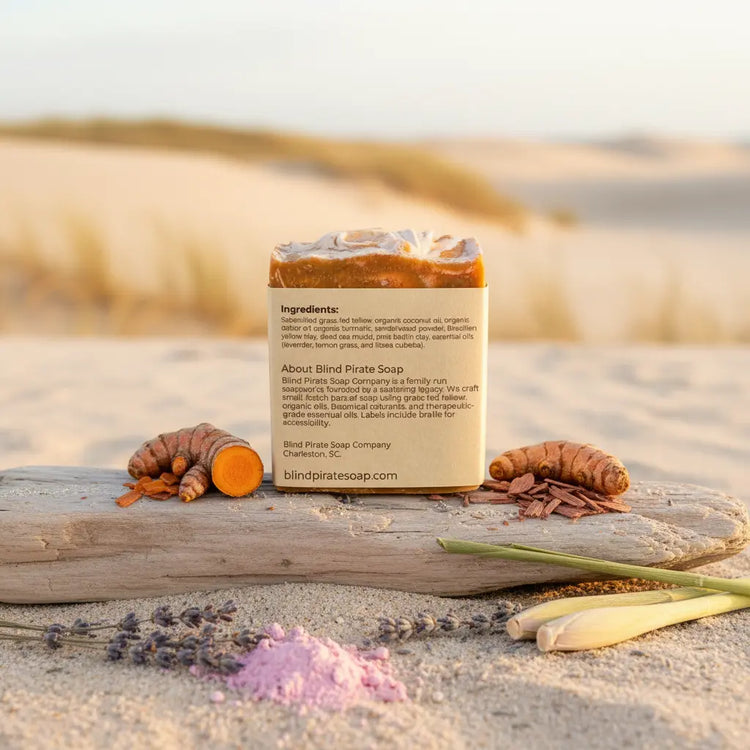 Back panel of Dune Grass tallow soap bar standing in warm dune sand, wild grasses swaying softly in the coastal breeze behind.