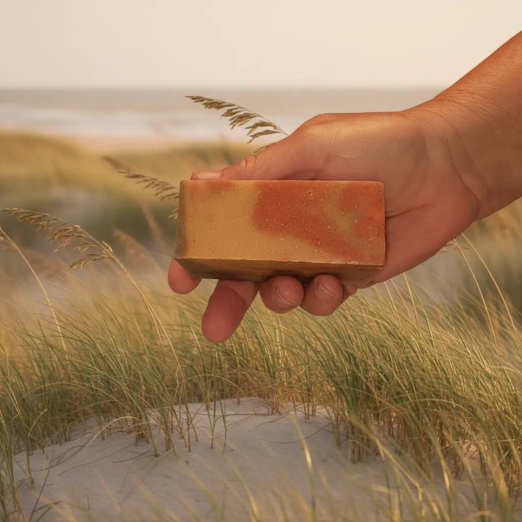Dune Grass Ballast Cut — warm terracotta and golden swirl, held against a sandy coastal dune scene.