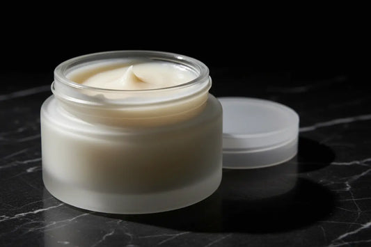 Ditch Kit clear lip balm by Blind Pirate Trading Co. in a frosted glass jar with lid off showing ivory white lip balm, photographed on dark marble with dramatic lighting.