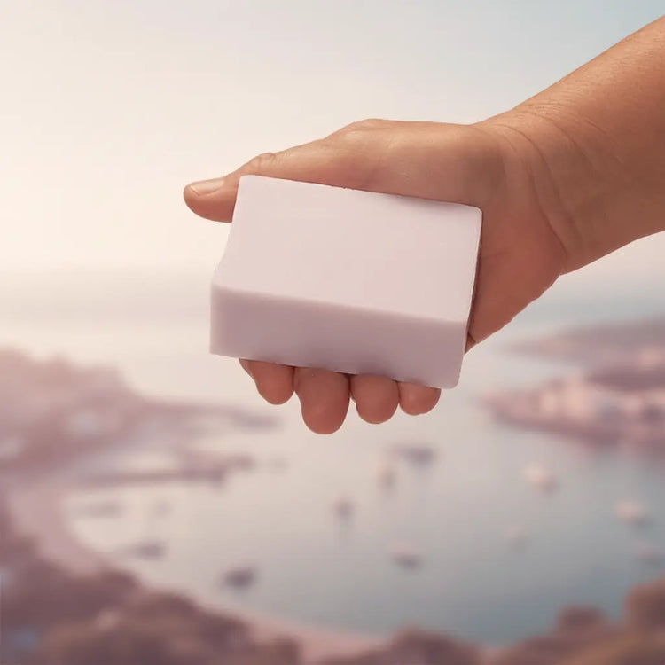 Windward Ballast Cut soap bar held in hand above a soft mauve coastal seascape, warm hazy light. Blind Pirate Trading Co.