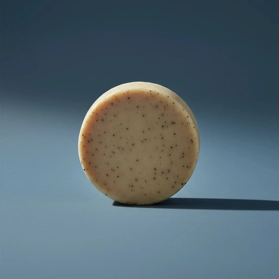 Beach Rain | Grass Fed Tallow | Shampoo Bar Blind Pirate Trading Co. a gorgeous, round and tan shampoo puc stands on it's side.