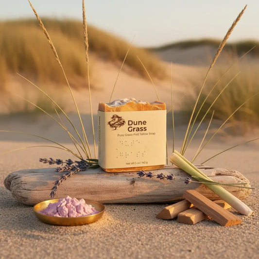 Dune Grass tallow soap bar front panel resting atop driftwood, wild lavender lemongrass scented bar framed by sweeping golden dunes behind.