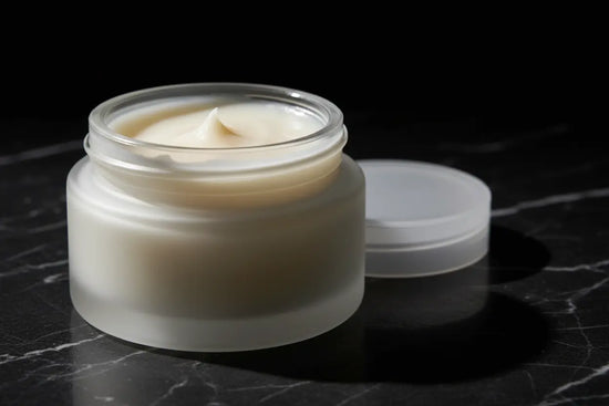 Ditch Kit clear lip balm by Blind Pirate Trading Co. in a frosted glass jar with lid off showing ivory white lip balm, photographed on dark marble with dramatic lighting.