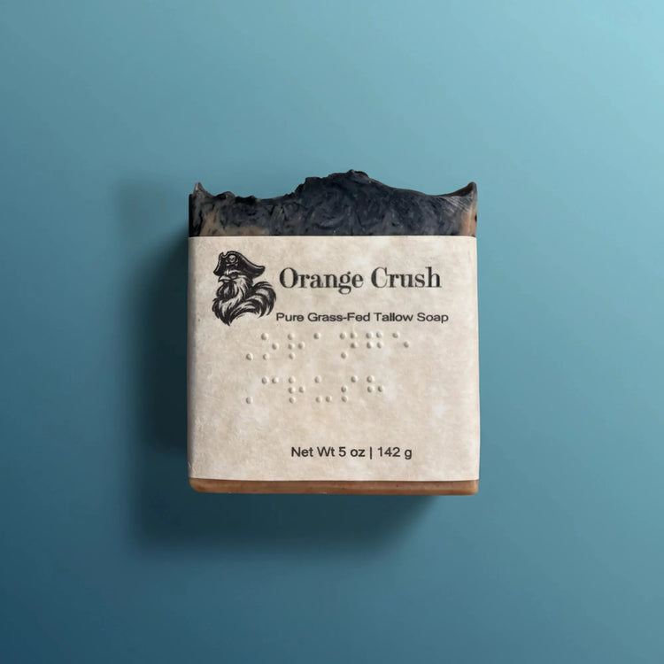 Orange Crush | Grass Fed Tallow Soap Bar Blind Pirate Trading Co. braille labeled on the front of the label.