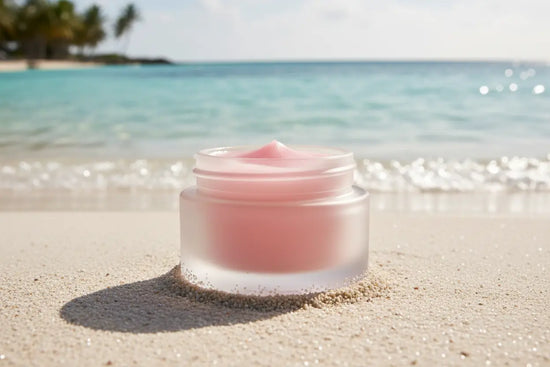 Ditch Kit rose tinted lip balm by Blind Pirate Trading Co. resting on white sand with crystal clear Caribbean turquoise water in the background.