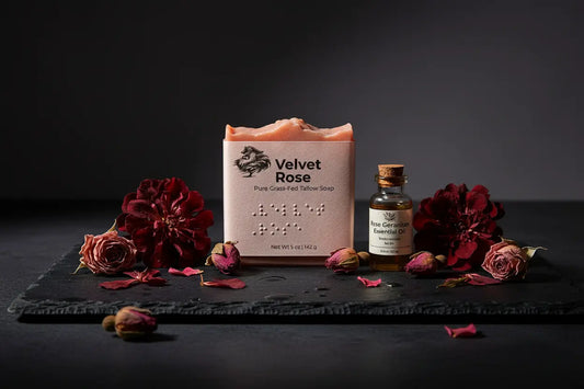 Velvet Rose on Black Slate dusky rose petals scattered close, a Geranium & Rose essential oil bottle alongside.
