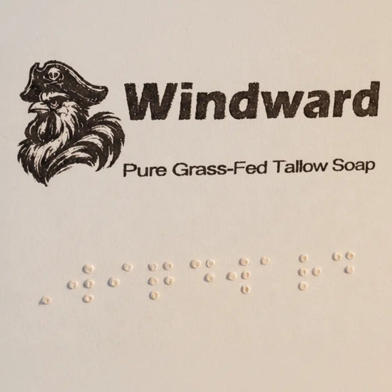 Windward label close-up — pirate logo, title, and full Braille block on pale kraft paper. Blind Pirate Trading Co.