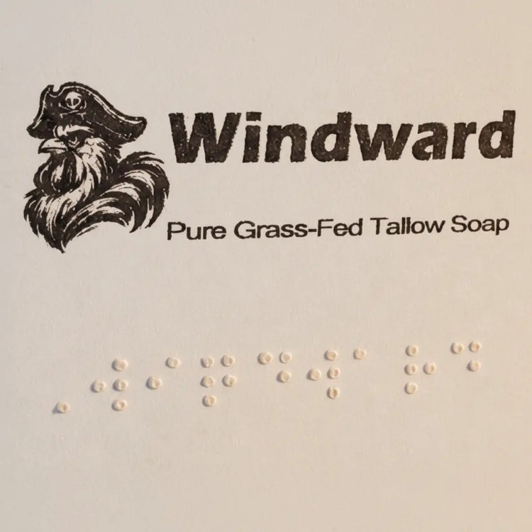 Windward label close-up — pirate logo, title, and full Braille block on pale kraft paper. Blind Pirate Trading Co.